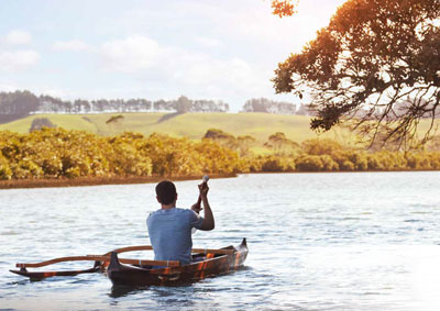 Man paddling waka on river